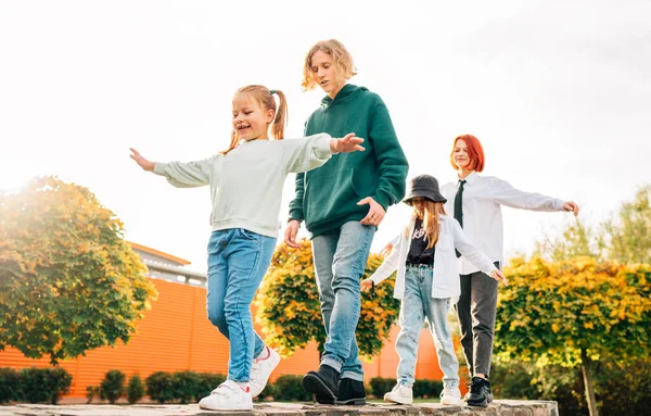 笑顔のティーンエイジャーの男の子と笑顔の姉妹の女の子子供たちが秋の日当たりの良い都市公園で連続して歩く — ストック写真