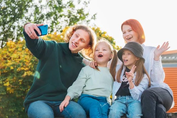 3人の笑顔の姉妹と弟の10代の肖像画は 現代のスマートフォンのカメラを使って自画像を撮る 不注意な幸せな若い十代の若者 子供の頃の時間と近代的な技術の概念イメージ — ストック写真