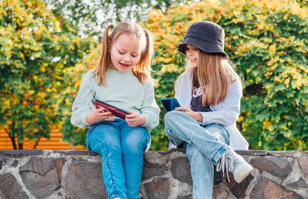 Twee Lachende Kleine Zusje Meisjes Kinderen Zitten Bladeren Hun Smartphone — Stockfoto
