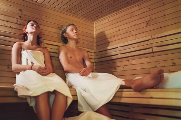 Casal Adolescentes Relaxantes Envolto Lençóis Brancos Deitados Suando Banco Madeira — Fotografia de Stock