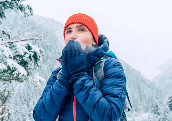 背包的女背包客穿着保暖的夹克 暖着手掌 一边走着冬天的山林小径 一边欣赏着雪山的风景 积极参加大自然活动的人的概念 — 图库照片