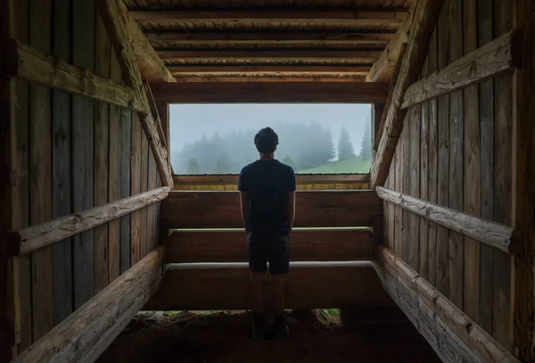 若い孤独な10代の少年は 木製の森の家の窓の近くに立って 朝のトウヒ霧の森を楽しむ 秋の旅行と観光 — ストック写真