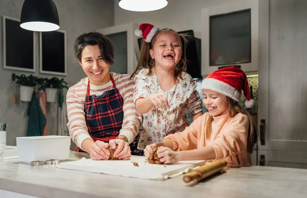 笑着的小女孩戴着红色的圣诞老人帽 妈妈在家里厨房一起揉搓圣诞姜饼面团 欢乐假期准备和童年概念 — 图库照片