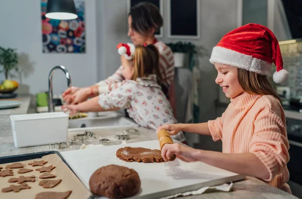 在家里厨房用滚动式别针揉搓圣诞姜饼面团 微笑着戴着红色圣诞老人帽的小女孩 温暖的家庭生活时刻 快乐的假日准备和童年的概念 — 图库照片