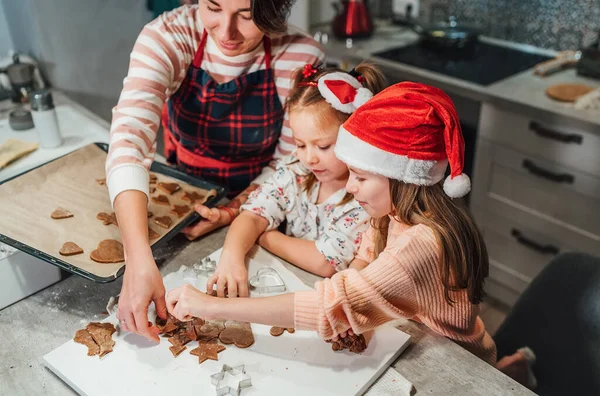 可爱的小女孩戴着红色的圣诞帽 妈妈在家里的厨房里一起用饼干切割机做自制面团圣诞姜饼 快乐的家庭假期准备 童年的概念 — 图库照片