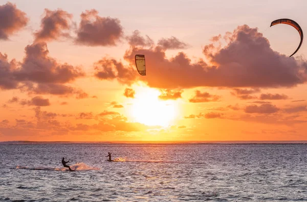 stock image Sunset sky over the Indian Ocean bay with a kiteboarder riding kiteboard with a green bright power kite. Active sport people and beauty in Nature concept image. Le Morne beach, Mauritius