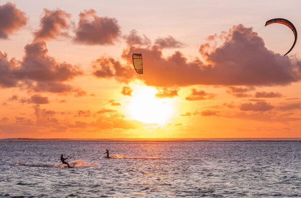 Sunset sky over the Indian Ocean bay with a kiteboarder riding kiteboard with a green bright power kite. Active sport people and beauty in Nature concept image. Le Morne beach, Mauritius