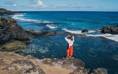 Lonely woman dressed light summer clothes enjoying Indian ocean view with strong surf on cliff at Gris Gris viewpoint extreme south of Mauritius island. Traveling around the world concept image. clipart