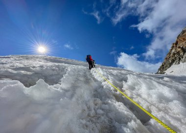 Güneşli bir günde Mont Blanc du Tacul 'un 4248m dağının altında, Fransa' nın Alpleri 'nin karlı yamaçlarında halat takımı olarak tepeye tırmanan iki dağcı. Spor, tırmanma, dağcılık konsepti.