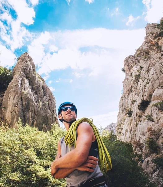 在帕克里卡公园 站在岩石悬崖墙之间的是一个面带微笑的登山者的画像 他戴着保护头盔 戴着太阳镜 肩上还戴着攀爬绳 积极的极限运动时间概念 — 图库照片