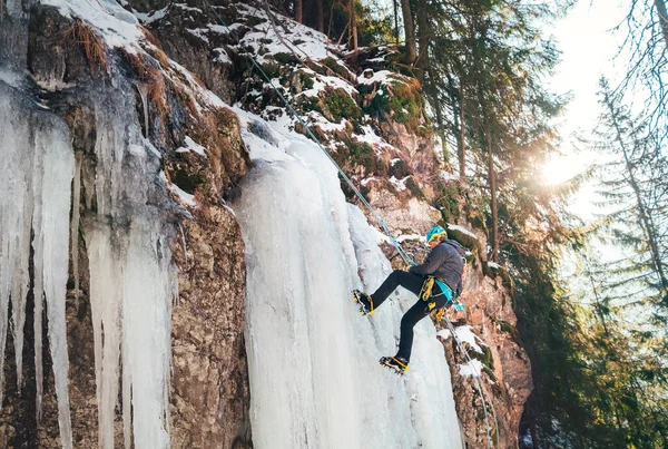 暖かい冬の登山服に身を包んだ氷の登山家は フリーズドウォーターフォールを放棄ハーネスとヘルメットを登る アクティブ人とスポーツ活動のコンセプトイメージ — ストック写真