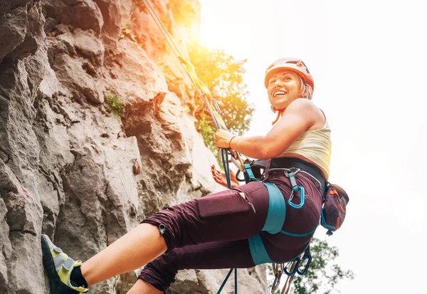 在克罗地亚的帕克莱尼察国家公园 身穿防护头盔和鞋子的女运动员用头顶绳索和安全带爬上悬崖石墙 微笑着 积极的极限运动时间概念 — 图库照片