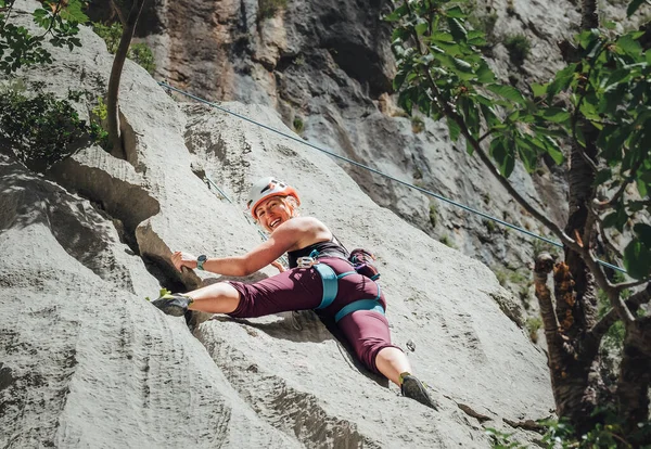 在克罗地亚的帕克莱尼察国家公园 身穿防护头盔的女运动员用上弦和攀爬带爬悬崖岩壁 积极的极限运动时间概念 — 图库照片