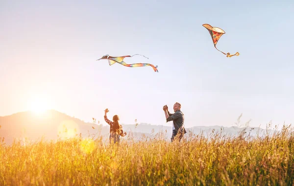 在高高的草地上放飞五彩缤纷的风筝时 带着女儿微笑着父亲 温暖的家庭夏季户外拍照或户外消磨时间的概念形象 — 图库照片