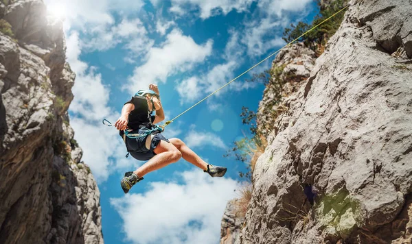 在克罗地亚的帕克里卡峡谷 一名戴着保护头盔的少年爬上了垂直的悬崖岩壁 用绳子环带装置 爬上了安全带 积极的极限运动时间概念 — 图库照片