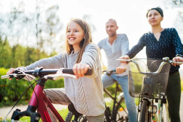 屋外自転車に乗っている間 父と母と一緒に長い髪の少女を笑顔 彼らは一緒に 幸せな親と子供時代を楽しんでいます アクティブスポーツライフコンセプトイメージ — ストック写真