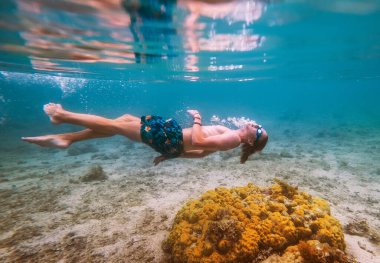 Diving teenage boy snorkeling in underwater glasses making bubbles over the coral reefs underwater photo in the clean turquoise lagoon on Le Morne beach on Mauritius island. Exotic traveling concept.