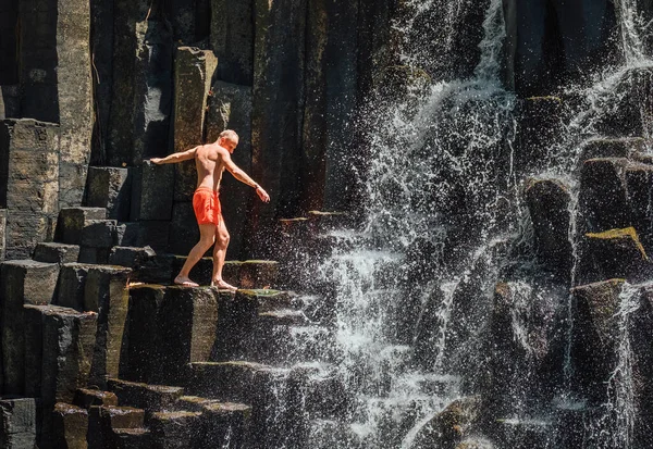 Caucasian Man Swimsuit Balancing Falling Water Streams Flowing Black Volcanic — Stockfoto