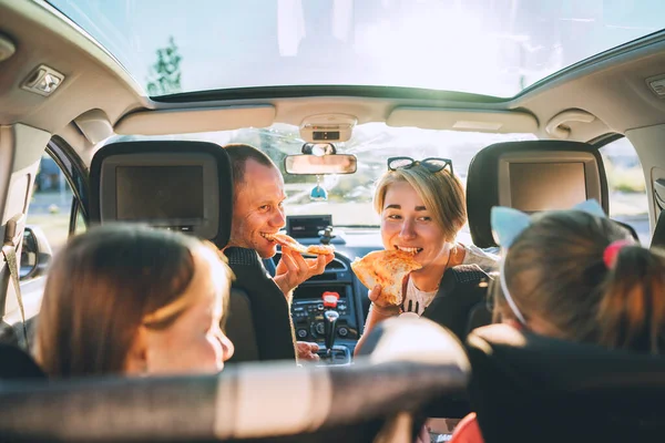透明屋根の現代的な車の中で座って調理されたイタリアのピザを食べている娘と若いカップル 幸せな家族の瞬間 子供時代 ファーストフードや自動車旅行のランチ休憩のコンセプトイメージ — ストック写真