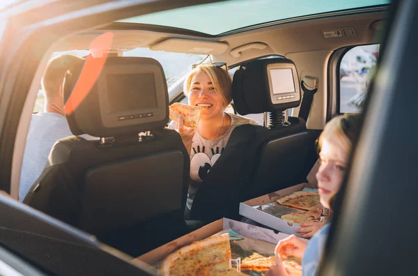 現代の車の中で家族と一緒に旅行中に調理されたイタリアのピザを食べる若い女性の肖像画 幸せな家族の瞬間と価値観 ファーストフードや自動車旅行のランチ休憩のコンセプトイメージ — ストック写真