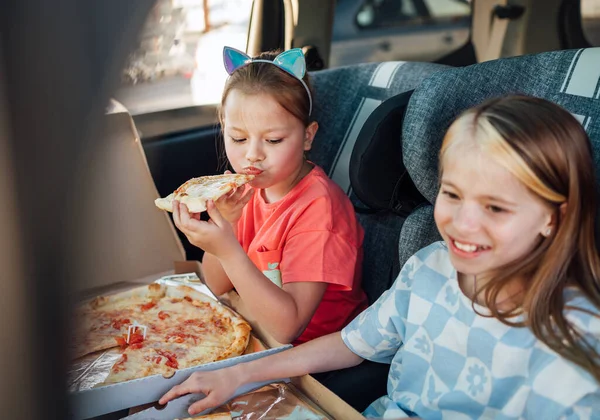 긍정적 미소짓는 자매들은 뒷좌석의 어린이용 카시트에 요리된 이탈리아 피자를 행복해 — 스톡 사진