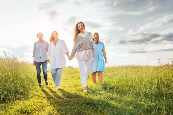 四个笑容满面的女人手牵着手走在青绿的草地上的画像 他们看着摄像机 女人的友谊 关系和幸福的概念形象 — 图库照片