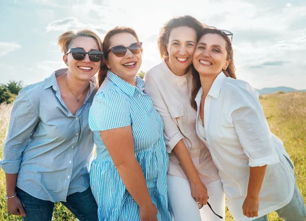在户外散步时 四个戴着太阳镜 带着明亮的阳光 抱着相机 看着镜头的快乐微笑的女人的画像 女人的友谊 关系和幸福的概念形象 — 图库照片