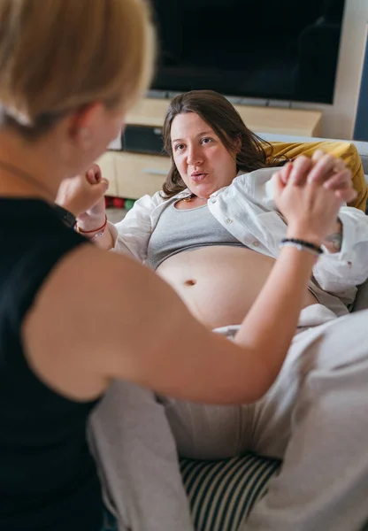 妊娠中の女性をサポートする若い女性のドゥーラは 自宅のリビングルームに大きな腹を持ちます 女性の健康 幸せな妊娠ドーラをサポートし 穏やかな精神的な気分の概念のイメージ — ストック写真