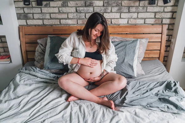 Young Pregnant Woman Sitting Cross Legged Tender Touching Belly Bed — Stock Photo, Image