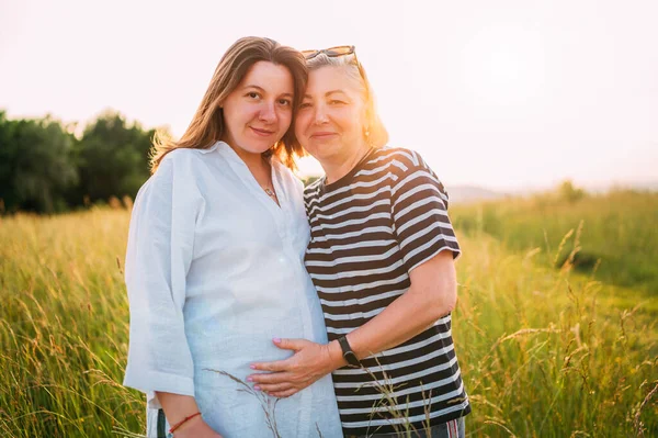 在黄昏时分 穿着浅色夏装 与母亲共赴夕阳的年轻孕妇形象 妇女健康 人在自然概念中的形象 — 图库照片
