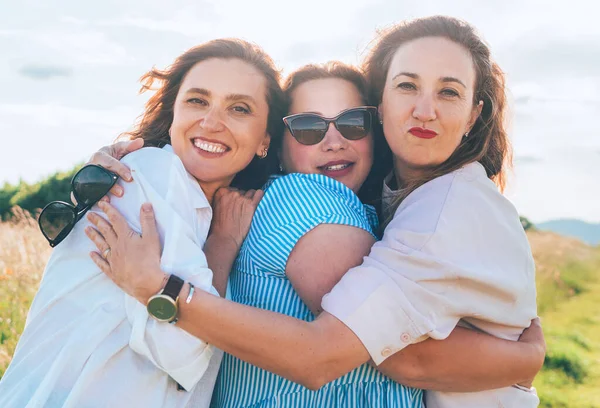 三个笑容满面的女人在户外散步时拥抱的画像 他们看着摄像机 妇女的友谊 关系和幸福概念形象 — 图库照片