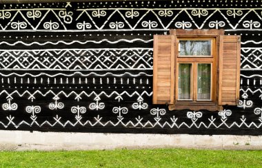Slovakya 'nın eski köyü Cicmany' deki koyu ahşap duvardaki beyaz ve siyah desenli süslemenin tahta penceresi. Avrupa tarihi mirası ve siyah beyaz arkaplan konsept görüntüsü