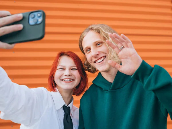 两个笑容满面的高加索青少年朋友的画像 男孩和女孩用智能手机摆姿势自拍 粗心大意的年轻人 时间与现代技术概念形象 — 图库照片