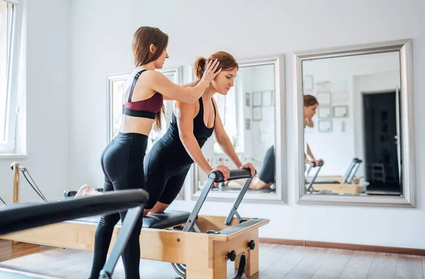 Instrutora Pilates Fêmea Jovem Ajudando Cliente Ajustar Postura Fazendo Exercícios — Fotografia de Stock