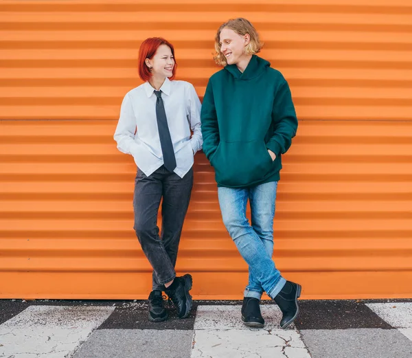 两个白人青少年朋友穿着休闲装站在橙色墙的背景上 两个人面带微笑的画像 年少无知与初恋观念 — 图库照片