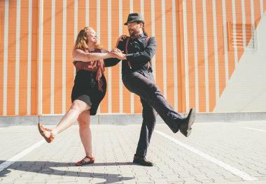Neşeli çift 1920-40 'larda Batı Yakası Swing döneminde çok popüler olan caz müziğiyle geçmişe dönük swing dansı yapıyordu. Çizgili duvar arka planının yanında birbirlerine gülümsüyorlar..