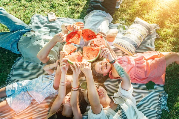 週末の晴れた日にピクニック毛布の上に寝そべっている両親の家族を持つ若い娘は 笑顔で笑って 赤いジューシーなスイカの作品を育てました 家族の価値観 果物のビタミン 屋外時間の概念 — ストック写真