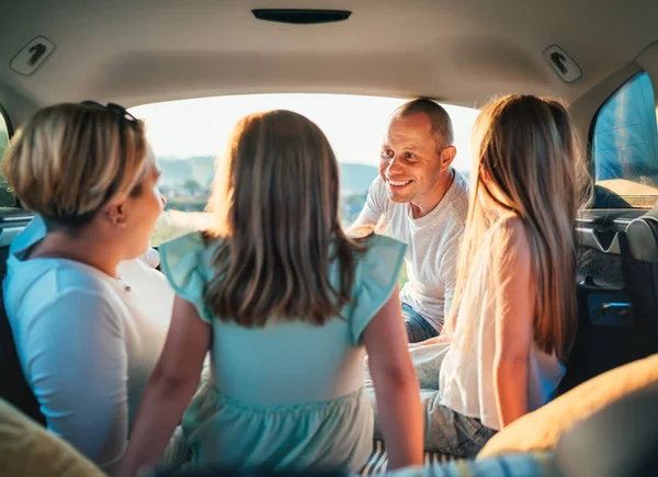 自動車トロフィーの間に車のトランクの中の2人の娘と幸せな若いカップル 笑ったり 笑ったり しゃべったりしている 幸せな笑顔の父親の肖像画 家族の価値観 旅行コンセプト — ストック写真