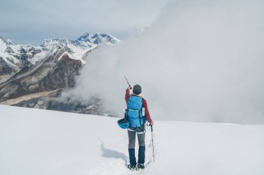 Sırt çantalı ve yürüyüş direkleriyle Mera zirvesinden 6000 metre yükseklikteki yamaçlara inen ve efsanevi Everest, Nuptse, Güney Suratlı Lhotse, Makalu güzel Yüksek Himalayalar 'ı işaret eden tırmanışçı..