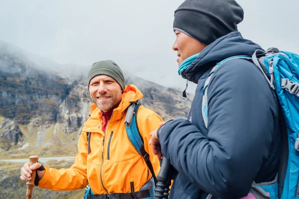 stock image Caucasian and Sherpa men with backpacks with trekking poles together smiling enjoying Mera peak climbing acclimatization walk  Makalu Barun Park route. Backpackers enjoying beautiful valley view