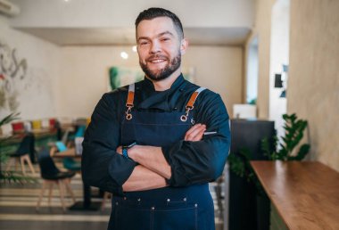 Küçük işletme sahibinin portresi. Siyah bir şef üniforması giymişti. Lokantasında önlüğü vardı. Başarılı insanlar, sıkı çalışma, tüketici kafeleri ve restoran endüstrisi konsepti.