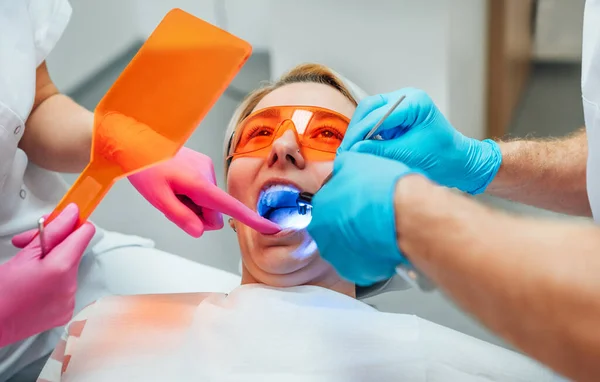 牙科诊所用紫外光治疗牙龈充填材料聚合过程中戴防护眼镜的年轻女性 医疗护理 牙齿美容业及医疗业概念 — 图库照片