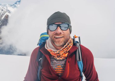 Güneş gözlüklü neşeli dağcı, sırt çantasıyla 6000 metre yükseklikteki Mera zirvesine tırmanıyor güneşli havanın keyfini çıkarıyor, yüksek Himalayalar 'da fiziksel bir meydan okuma. Kuzey-Doğu Nepal.