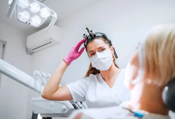 现代医疗病房的牙科诊所病人预约 牙科医生戴着放大镜 微笑着与年轻的女医生对视 准备接受牙齿手术 医疗保健和医疗行业概念形象 — 图库照片