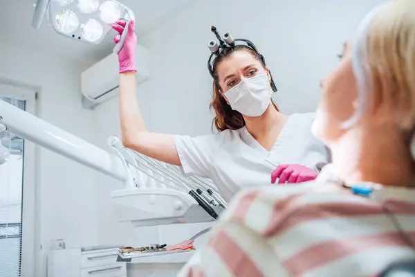 现代医疗病房的牙科诊所病人预约 牙科医生戴着放大镜 对着准备做牙手术的年轻女性用牙光 医疗保健和医疗行业形象 — 图库照片