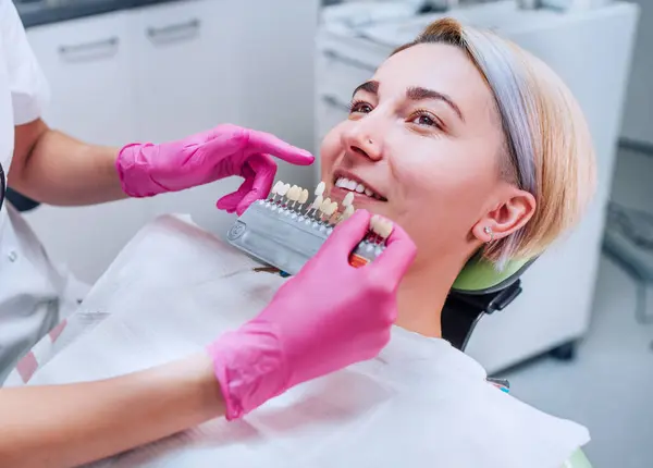 年轻女性坐在口腔科诊所的椅子上 微笑着露出她的牙齿 牙科医生选择带有阴影标签的牙齿颜色 医疗保健 口腔卫生和医疗行业概念形象 — 图库照片