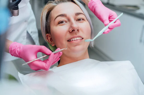 中年妇女坐在口腔科椅子上 戴着粉色手套 戴着挖掘机和镜像医疗工具的优雅牙医手掌的画像 医疗保健和医疗行业概念形象 — 图库照片