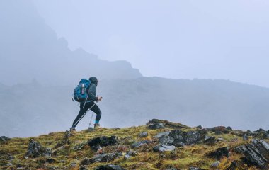 Sırt çantalı ve yürüyüş direkleri olan yalnız bir kadın, Nepal 'deki Tuli Kharka yerleşim alanı yakınlarındaki Makalu Barun Ulusal Parkı' nda dağ yolundan gidiyor. Dağ yürüyüşü ve aktif insan konsepti.