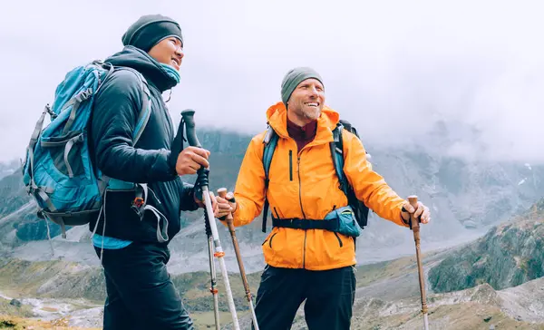 コカシアンとシェルパの男性は一緒にトレッキングポールとバックパックを持ち メラピーククライミングを楽しみながら笑顔で歩くマカルバランパークルート 美しい渓谷の景色を楽しむバックパッカー ストックフォト