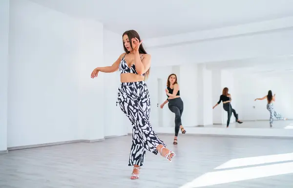 優雅なダンスの女性グループは大きな鏡の壁が付いている白い色の広々としたホールで優雅なダンスの動きをする ダンスの間に人々の表情 女性の体の美しさ アクティブなライフスタイルの概念イメージ ストック画像